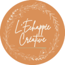 Logo l'échappée créative typographie à main levée blanc cassée sur fond orange rouille. Texte entouré d'une couronne de fleurs et feuillages écru. Soulignage de couleur vert olive pâle